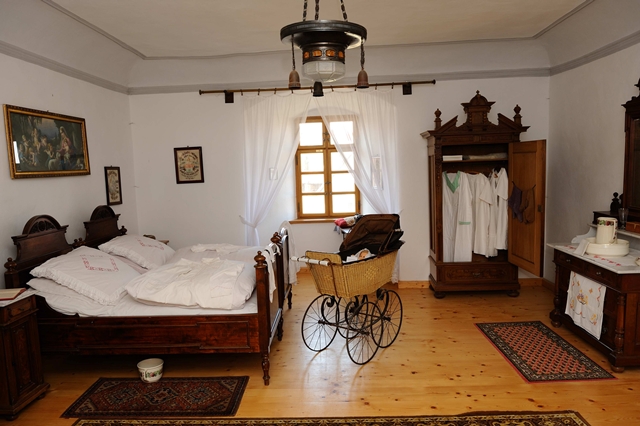 Bild vom Heimatmuseum mit einem historisch eingereichteten Zimmer mit Schrank, Ofen und Schlafgelegenheit