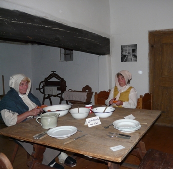 Bild aus dem Schloss einer Erlebnisführung - mit zwei Frauen, die an einem großen Tisch sitzen und das Essen zubereiten