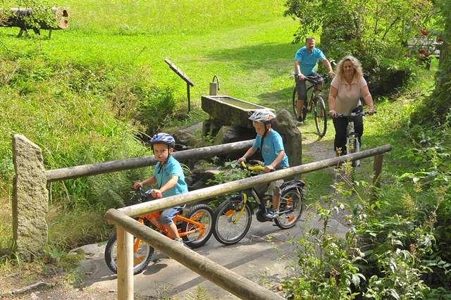 Eine Familie auf Farradtou überquert gerade eine hölzerne Brücke