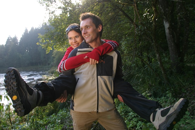 service Foto eines Wander-Pärchens - er hält sie am Rücken Huckepack und sie streckt die Beine in die Luft